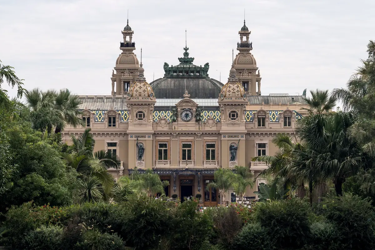 The ornate facade of the Casino de Monte-Carlo with its twin towers, behind palms and gardens