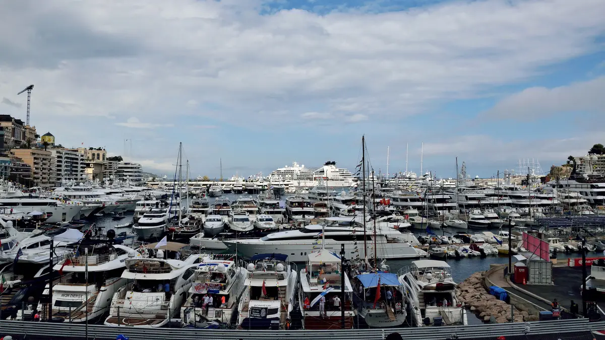 Port Hercule packed with yachts on Grand Prix race day, under a wide sky with the town behind