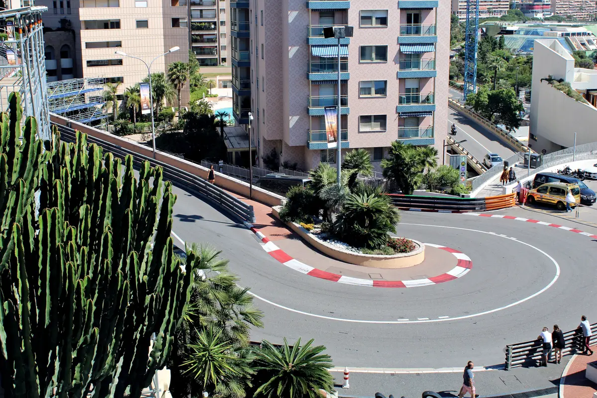 The tight hairpin bend of the Grand Prix circuit with red and white kerbs, seen from above beside tall cacti