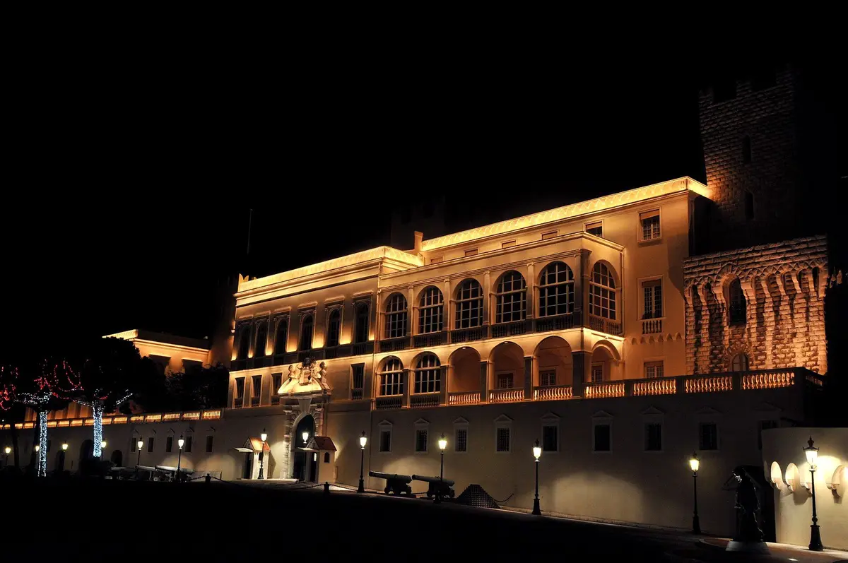 The facade of the Prince’s Palace lit warm gold against a black night sky