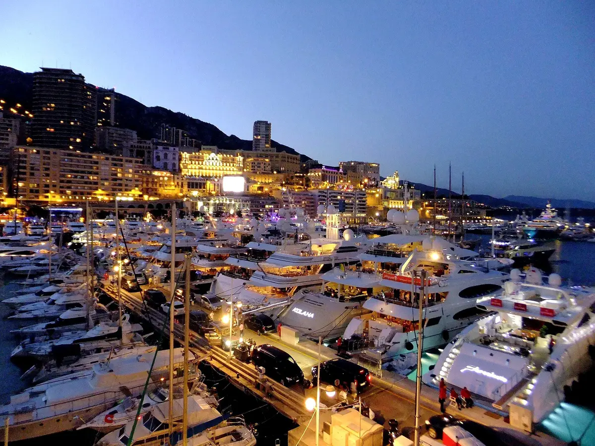 Yachts moored in Port Hercule at blue hour, with the lights of Monte-Carlo coming on along the hillside