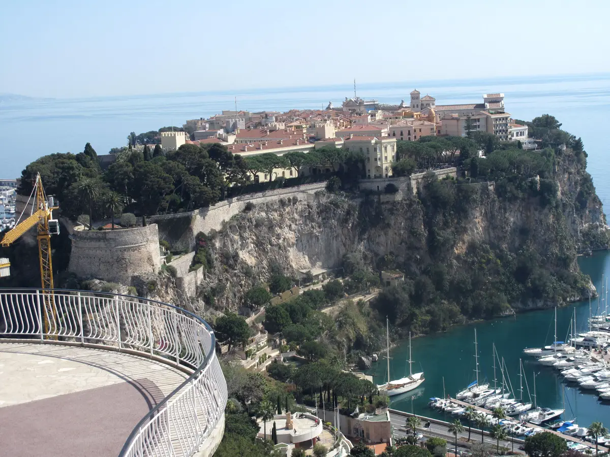 The sheer cliff of the Rock with the old town along its top, above the boats of Port Hercule